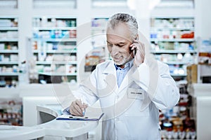 Bearded mature sunburnt man in a white coat speaking on the phone