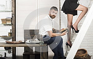 Bearded man read book with female legs on ladder