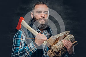 Bearded middle age male holds an axe and firewoods.