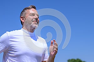 Bearded middle-aged man grinning happily as he jogs outdoors