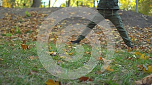 Bearded middle-aged man in khaki clothes doing chinese tai chi exercises on lawn in autumn city park