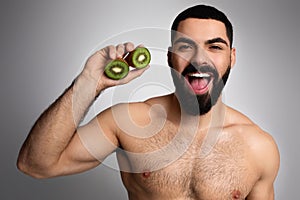 Bearded middle eastern man holding kiwi halves in his hand