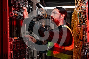Bearded network technician inspecting servers in data center