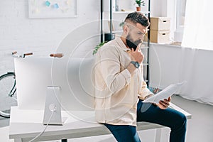 Bearded office worker watching at papers and thinking