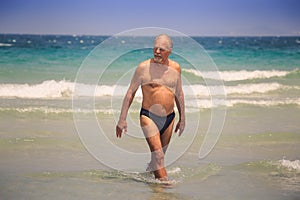 Bearded Old Man Walks out of Sea against White Foamy Waves