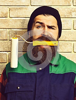 Bearded painter man holding roller paint with satisfied face