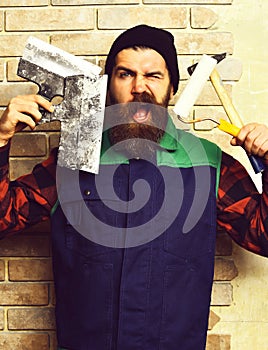 Bearded painter man holding various building tools with satisfied face