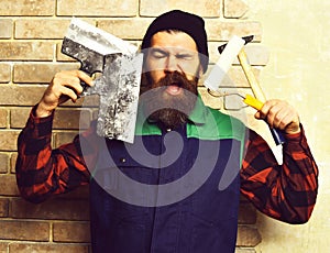 Bearded painter man holding various building tools with satisfied face