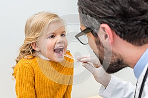 bearded pediatrist checking throat of adorable