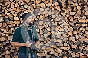 Bearded photographer nature with digital camera on firewood wall background.