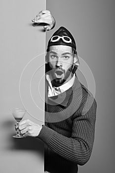 Bearded pilot with cocktail in glass on red green studio background