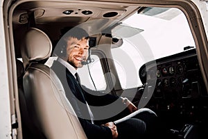 Bearded pilot in formal wear sitting in plane