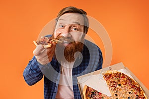 Bearded Redhaired Guy Eating Slice Of Tasty Pizza, Orange Background