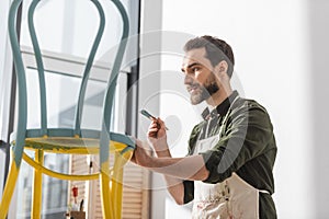 Bearded restorer in apron holding paintbrush