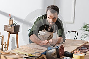 Bearded restorer sanding surface of wooden