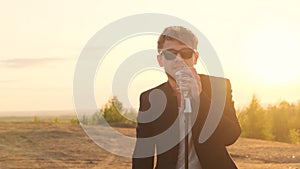 bearded rock star singer with black glasses sing expressive song in retro microphone. man with stubble or beard in black