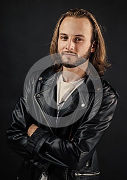 bearded rocker in leather jacket. man with long hair. rock style fashion. stylish brutal man hipster.