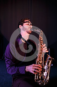 Bearded saxophonist in glaces. Saxophone on a foreground photo