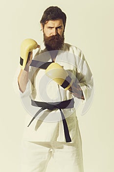 Bearded serious karate man in kimono and boxing gloves