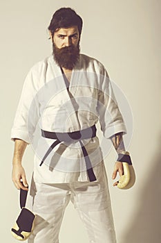 Bearded serious karate man in kimono and boxing gloves