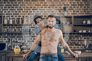 Bearded shirtless man and his girlfriend hugging in kitchen