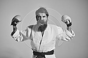 Bearded shouting happy karate man in kimono and boxing gloves