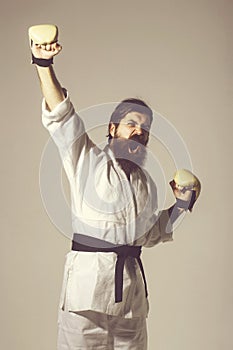 Bearded shouting happy karate man in kimono and boxing gloves