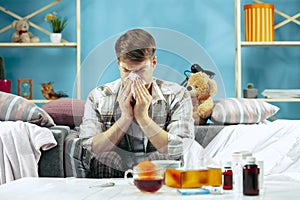 Bearded sick man with flue sitting on sofa at home. Illness, influenza, pain concept. Relaxation at Home. Healthcare