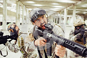 Bearded soldier is screaming and yelling. He has long rifle in his hands. Guy is standing in front of his combats. They