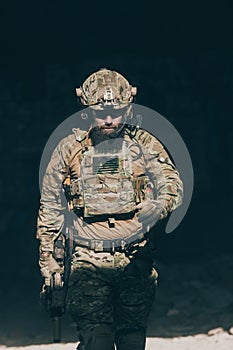 A bearded soldier in a special forces uniform walks through an abandoned building after a successful mission. Selection