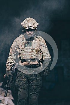 A bearded soldier in a special forces uniform walks through an abandoned building after a successful mission. Selection