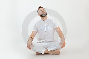 Bearded sporty handsome man tutor sit in lotus posture, on white background. Yoga zen and eastern philosophy. Meditation