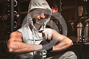 A bearded sporty man in the gym is meditating in a lotus position.