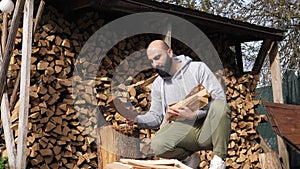 Bearded strong man with a log and a sharp vintage axe chop wood and put them together for fire heat. Detail of axe