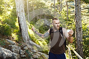 Bearded stylish hiker man using gps navigation for positioning at the mountain trail and thinks where to go. Technology