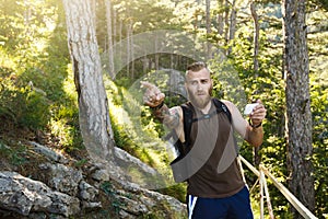 Bearded stylish hiker man using gps navigation for positioning at the mountain trail and thinks where to go. Technology
