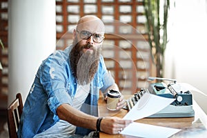 Bearded stylish writer with cup of coffe reading his novel