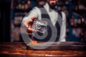 Bearded tapster demonstrates the process of making a cocktail behind bar
