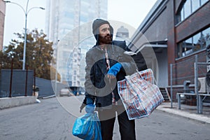 Bearded tramp man with bag on city street