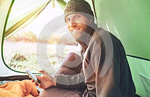 Bearded traveler Man uses his mobile phone sitting in tent