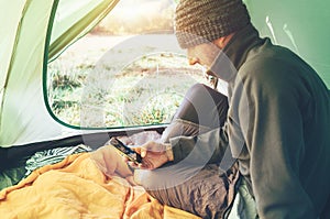 Bearded traveler Man uses his mobile phone sitting in tent photo