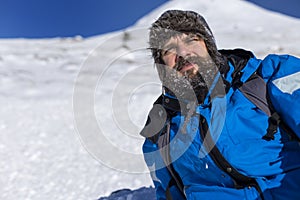 Bearded trekker resting while climbing in winter