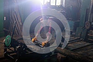 bearded worker in protective gloves pushing machine