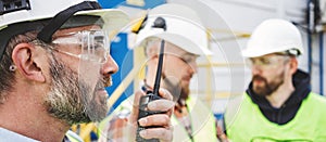 Bearded worker wearing helmet and protective glasses control process of production