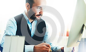 Bearded young businessman working on modern office. Consultant man thinking looking in monitor computer. Manager typing