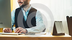 Bearded young businessman working on modern office at night. Consultant man thinking looking in monitor computer. Manager typing o