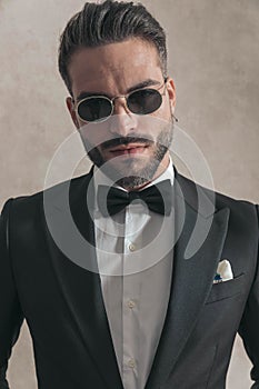 Bearded young man in elegant tux with glasses posing