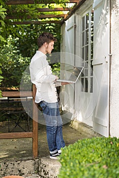 Bearded young man looking his laptop computer under the pergola