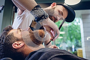 Bearded young man ready for shaving in the hair salon of a skilled barber