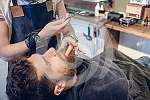 Bearded young man ready for shaving in the hair salon of a skilled barber photo